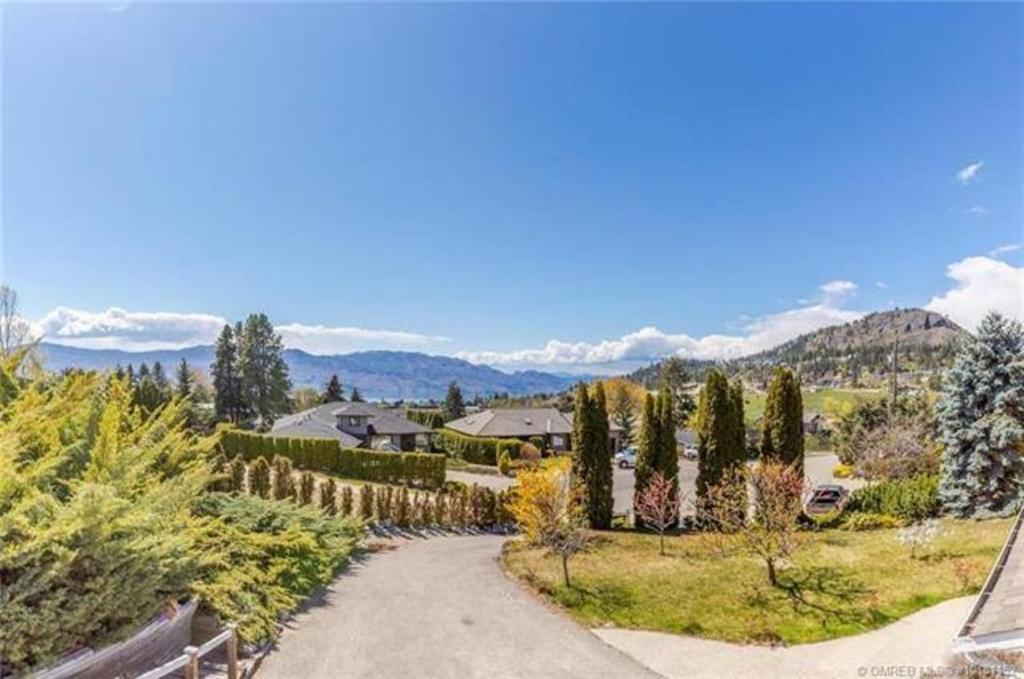 a driveway leading to a house with mountains in the background at Rodee Homestay in West Kelowna