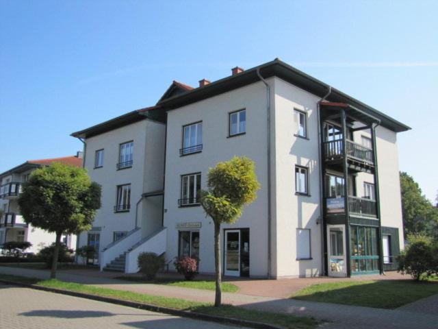 ein großes weißes Gebäude mit einem Baum davor in der Unterkunft Ferienwohnung am Maiglöckchenberg in Ostseebad Karlshagen