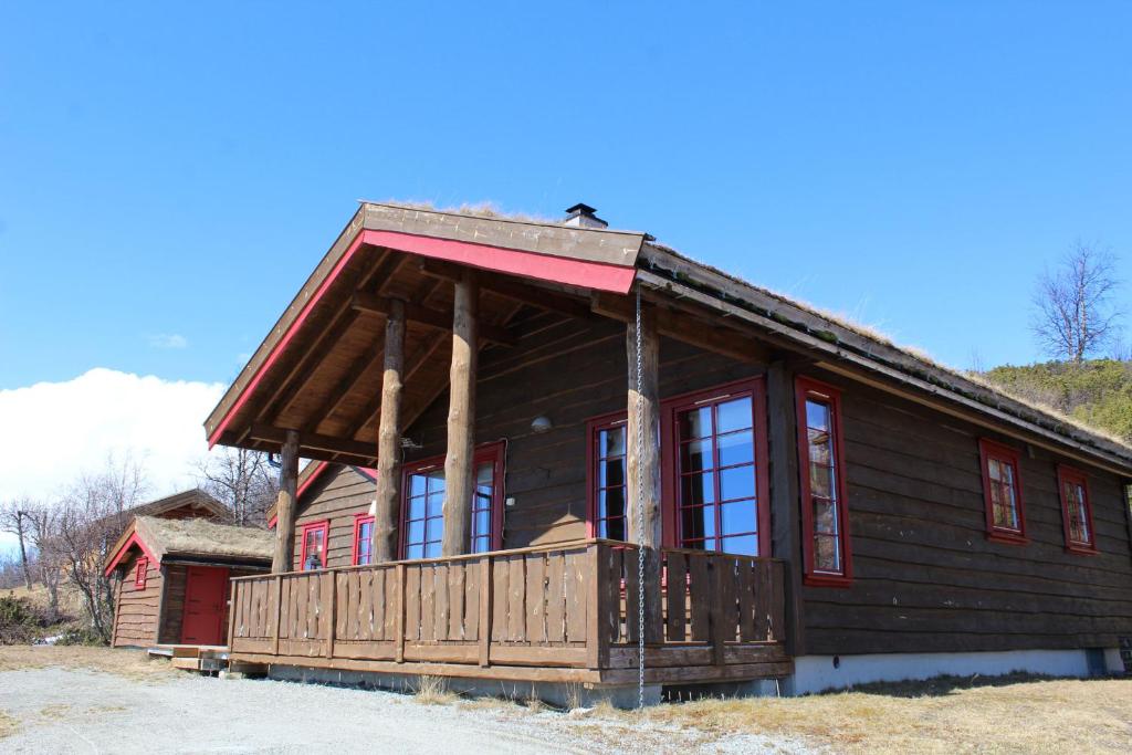 a log cabin with a balcony and red windows at Solberg 10 persons cabin in Myro