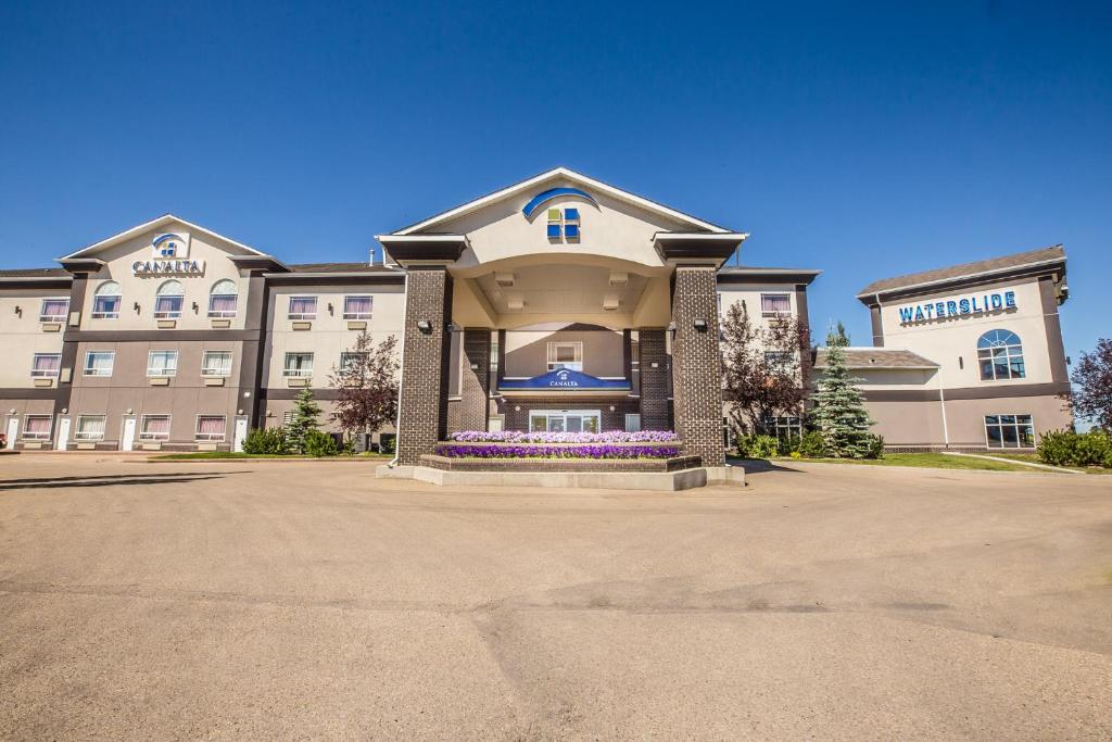 a large building with purple flowers in front of it at Canalta Camrose in Camrose