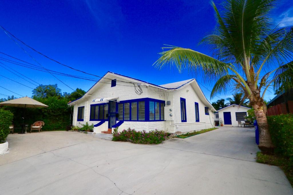 a white house with blue shutters and a palm tree at Pousada Host4U in Miami