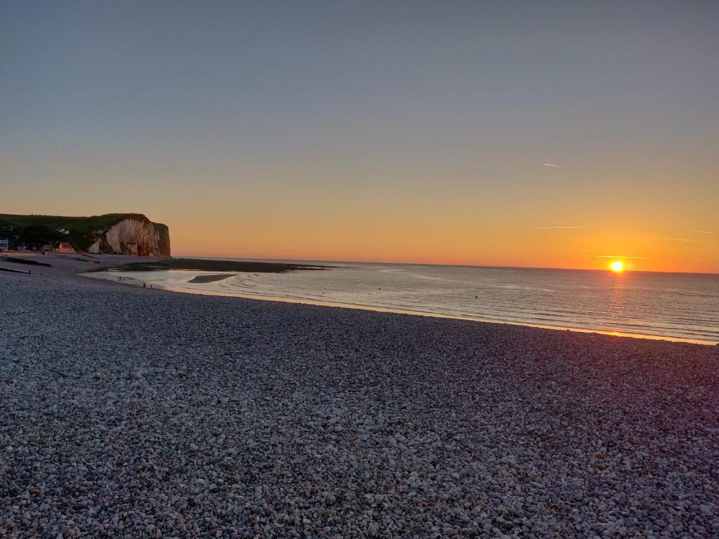 a sunset on a beach with the sun setting over the ocean at Chaumière d'Albâtre - Gîte-Entre terre et Mer in Ourville-en-Caux