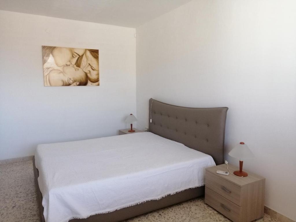 ピッツォルンゴにあるA Due Passi Dal Mareのベッドルーム1室(ベッド1台付)が備わります。壁に絵が飾られています。