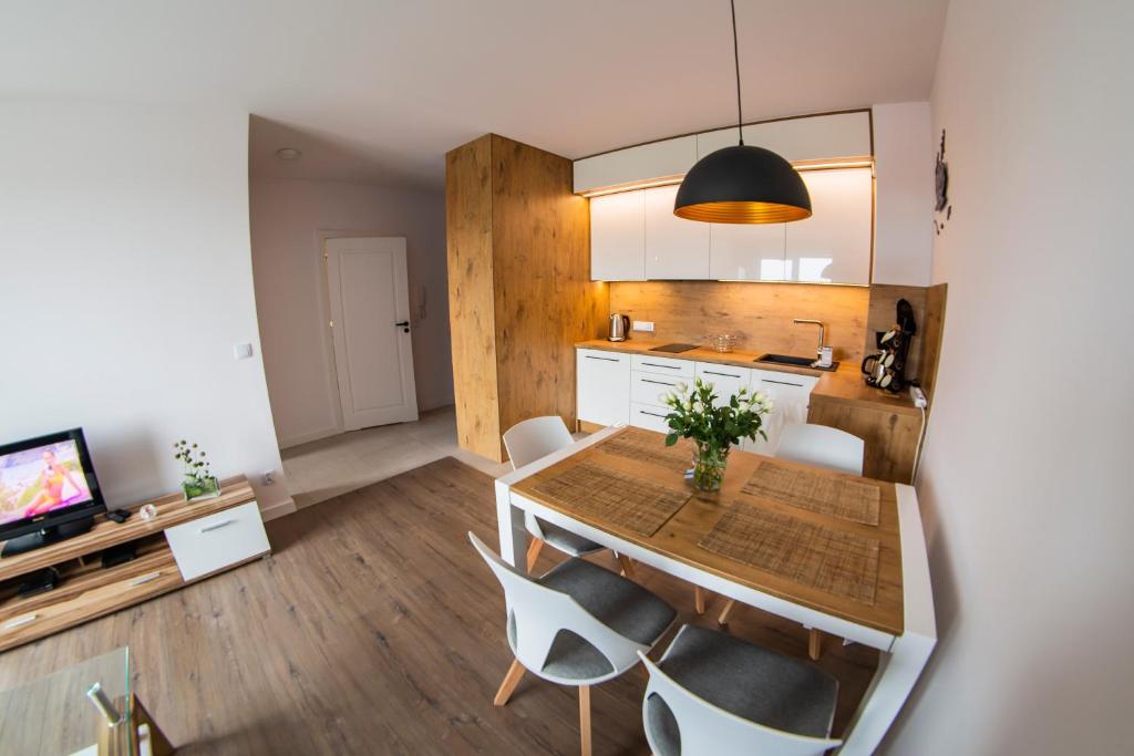 cocina y comedor con mesa de madera y sillas en Morze-kwatery Apartament Bel Mare, en Międzyzdroje