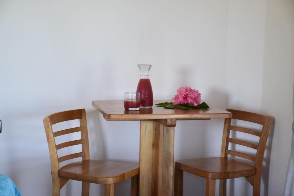 a table with two chairs and a bottle and flowers on it at Takarua Lodge in Hanga Roa
