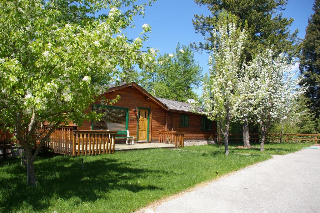 Cabaña de madera con porche y árboles en Creekside Cabin en Fairmont Hot Springs