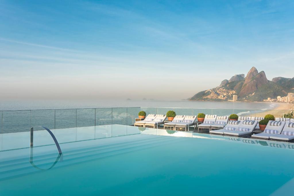 a swimming pool with chairs and a view of the ocean at Hotel Fasano Rio de Janeiro in Rio de Janeiro