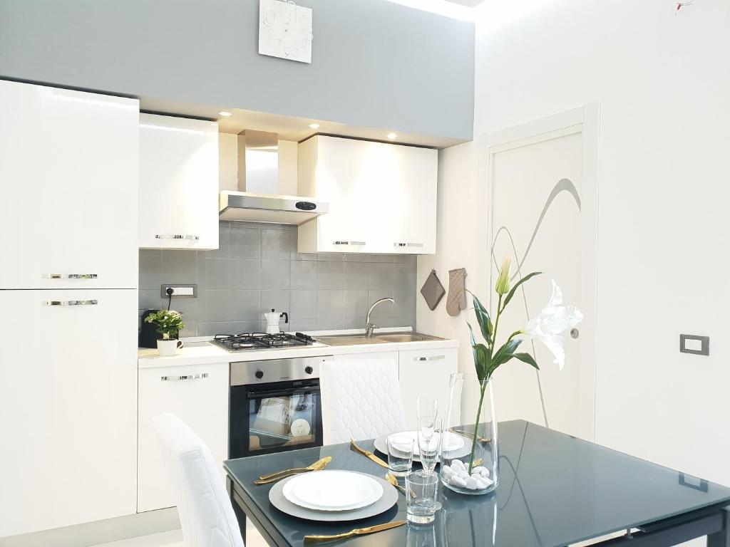 a kitchen with white cabinets and a table with plates on it at Sea Elegance in Oliveri