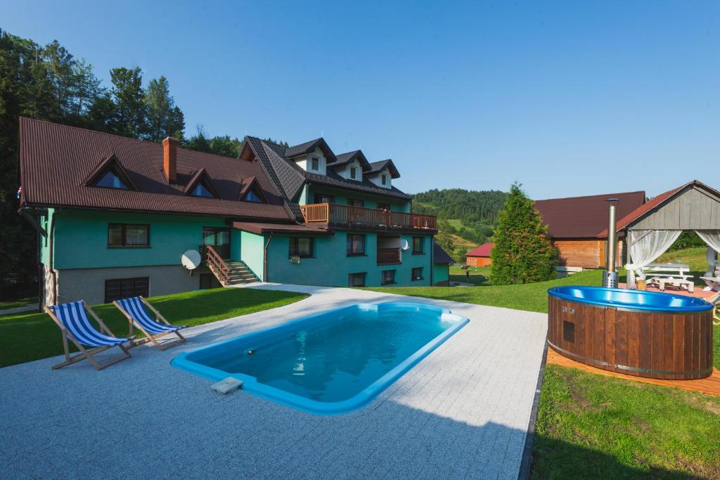 a swimming pool with two chairs and a house at Agroturystyka u Chlebków in Ochotnica Górna