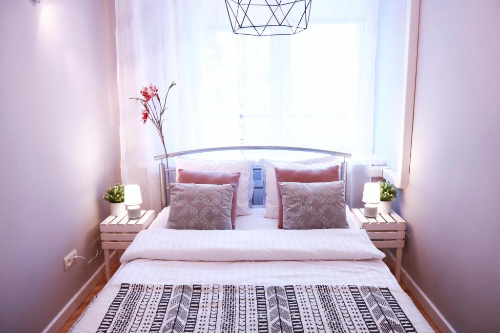 een slaapkamer met een bed met roze kussens en een raam bij Chill & Explore by Cooee Apartments in Warschau