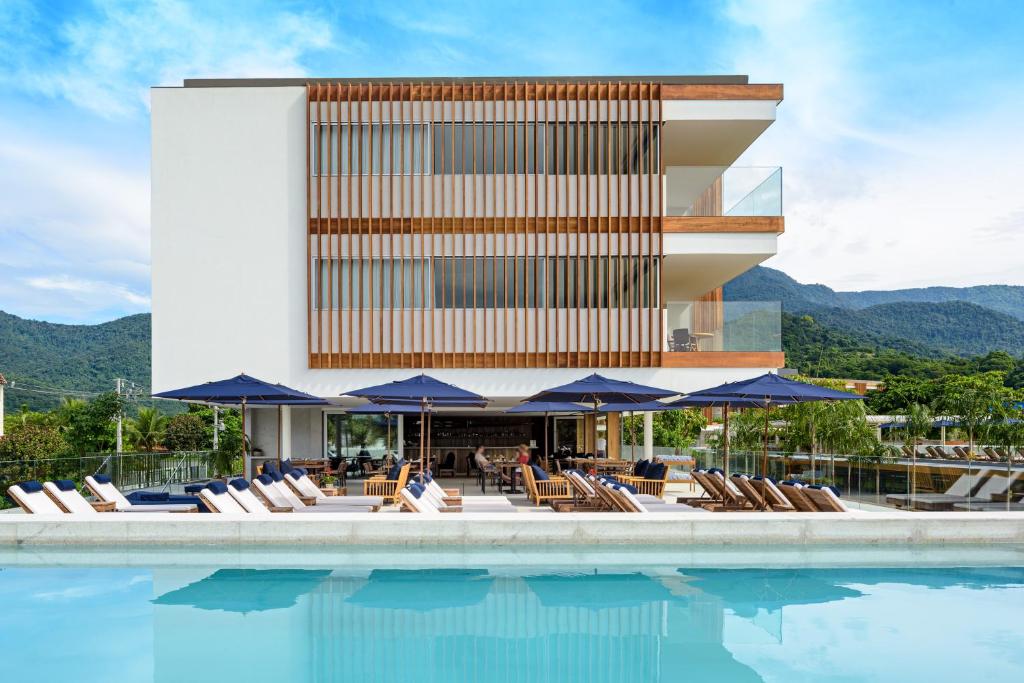 a pool with chairs and umbrellas next to a building at Hotel Fasano Angra dos Reis in Angra dos Reis