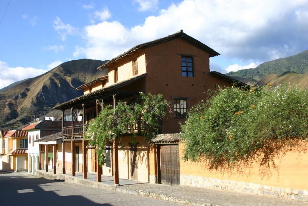 een gebouw op een straat met bergen op de achtergrond bij Avalon Hostal Boutique in Vilcabamba