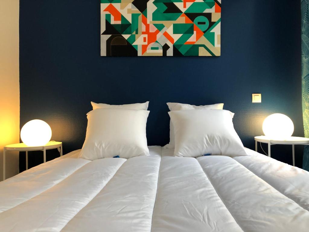 - un lit avec des draps et des oreillers blancs dans une chambre dans l'établissement City'IN Appart, à Carcassonne