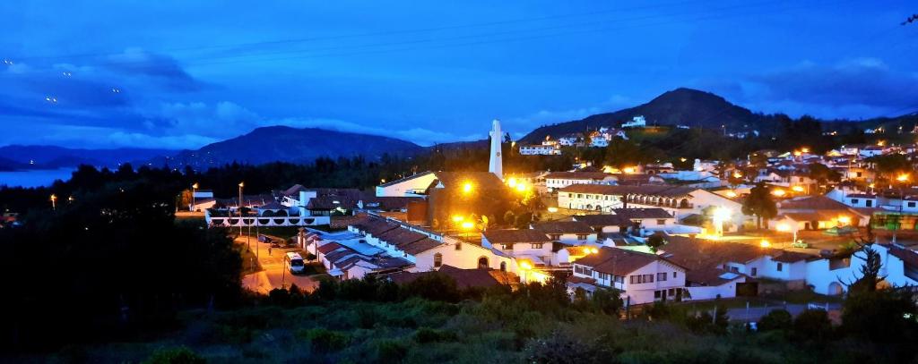 uma cidade iluminada à noite com montanhas ao fundo em Living Club em Guatavita