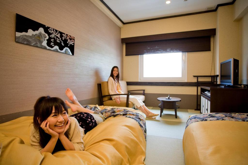 a woman laying on a bed in a hotel room at Takayama Ouan in Takayama