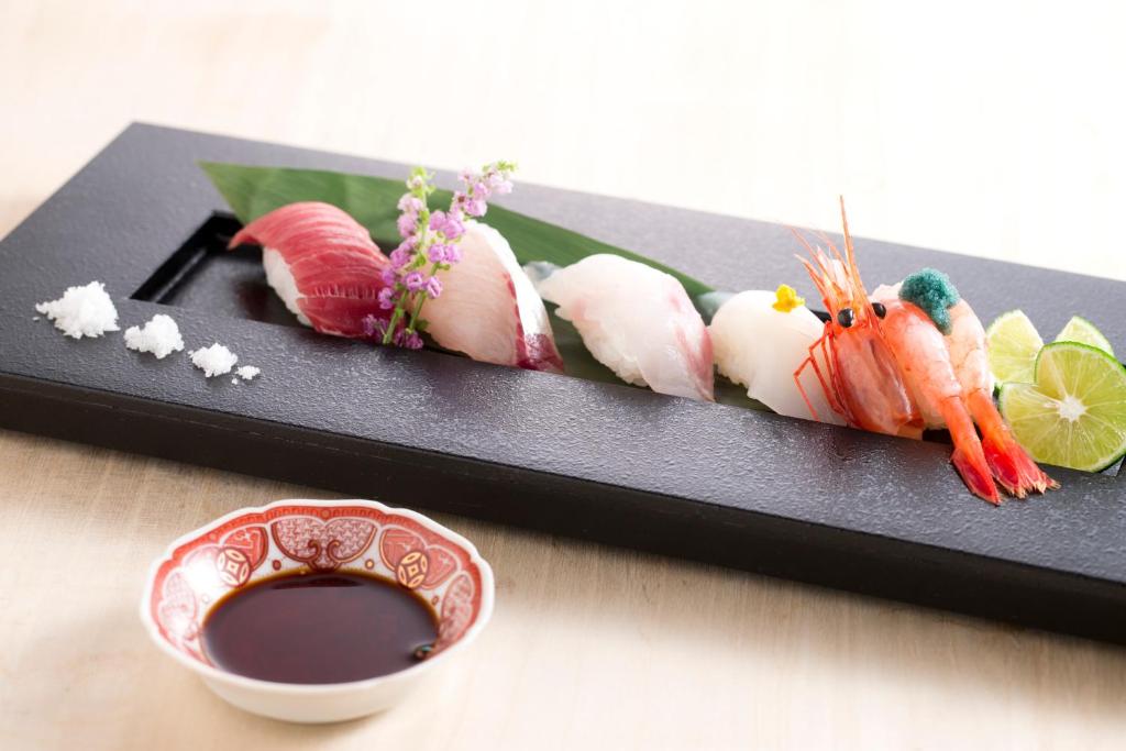 un plato de comida con sushi y un tazón de salsa de soja en Matsusaki, en Nomi