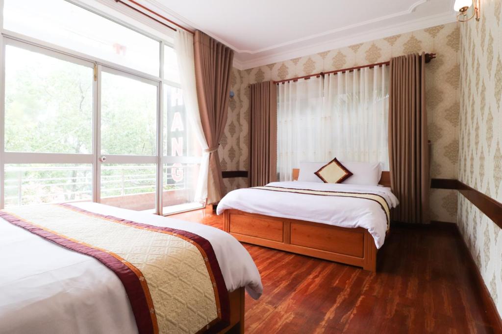 a bedroom with two beds and a large window at MINE Da Lat Hotel in Da Lat
