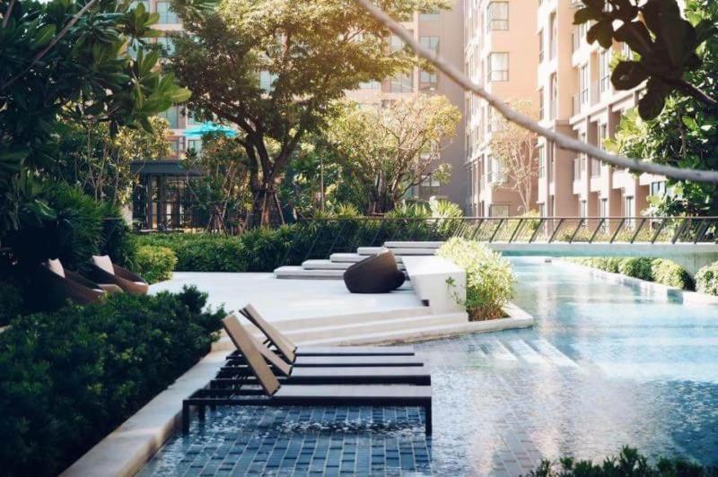 - un jardin avec un banc et une piscine d'eau dans l'établissement Rain condo ChaAm HuaHin by AY B311, à Cha Am