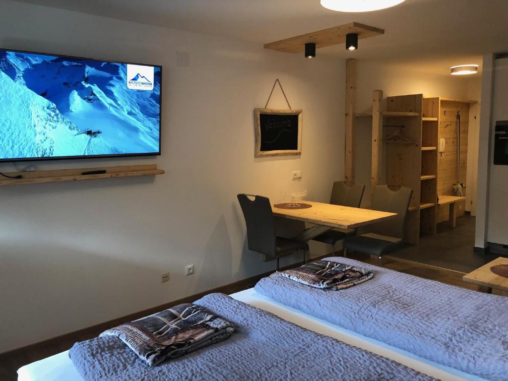 Pokój z 2 łóżkami i telewizorem na ścianie w obiekcie Julia w Kaprunie