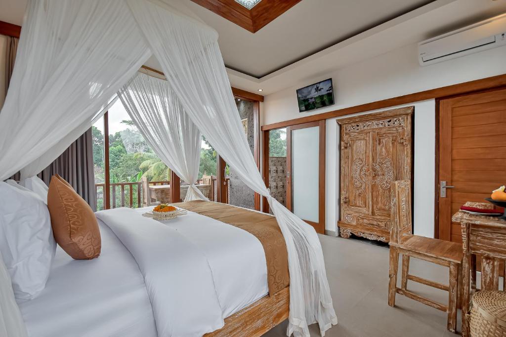a bedroom with a white bed and a balcony at Santosha Place in Ubud