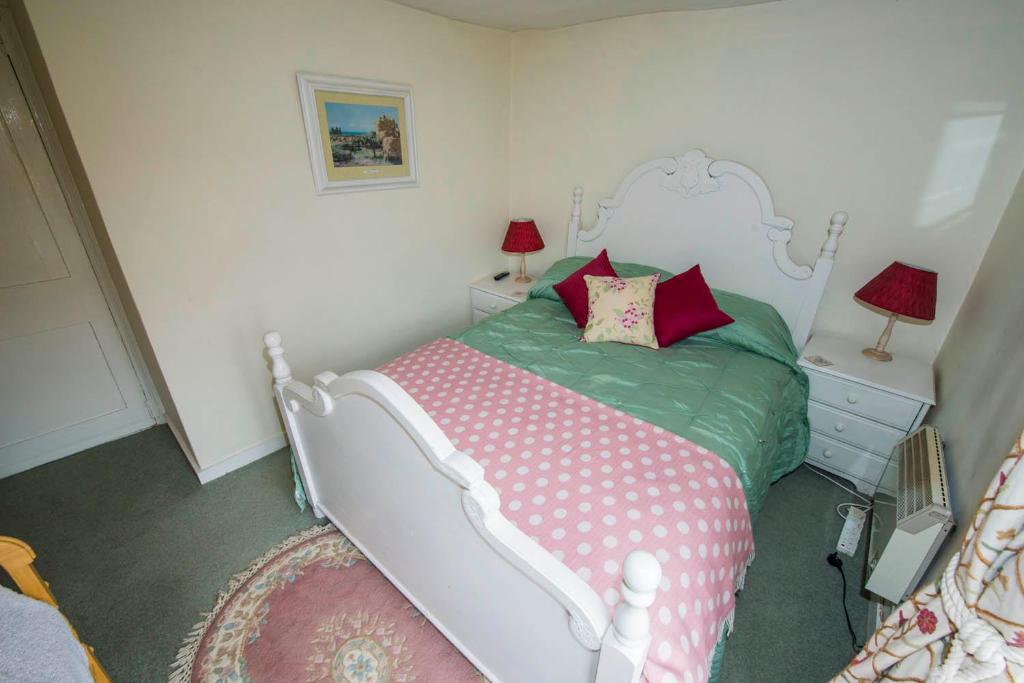 a bedroom with a white bed with red pillows at Pebble Cottage in Holt