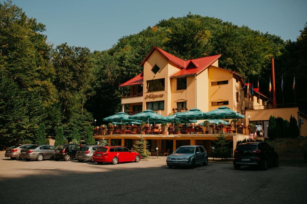 a building with umbrellas and cars parked in a parking lot at Pensiunea Magura in Baia Mare