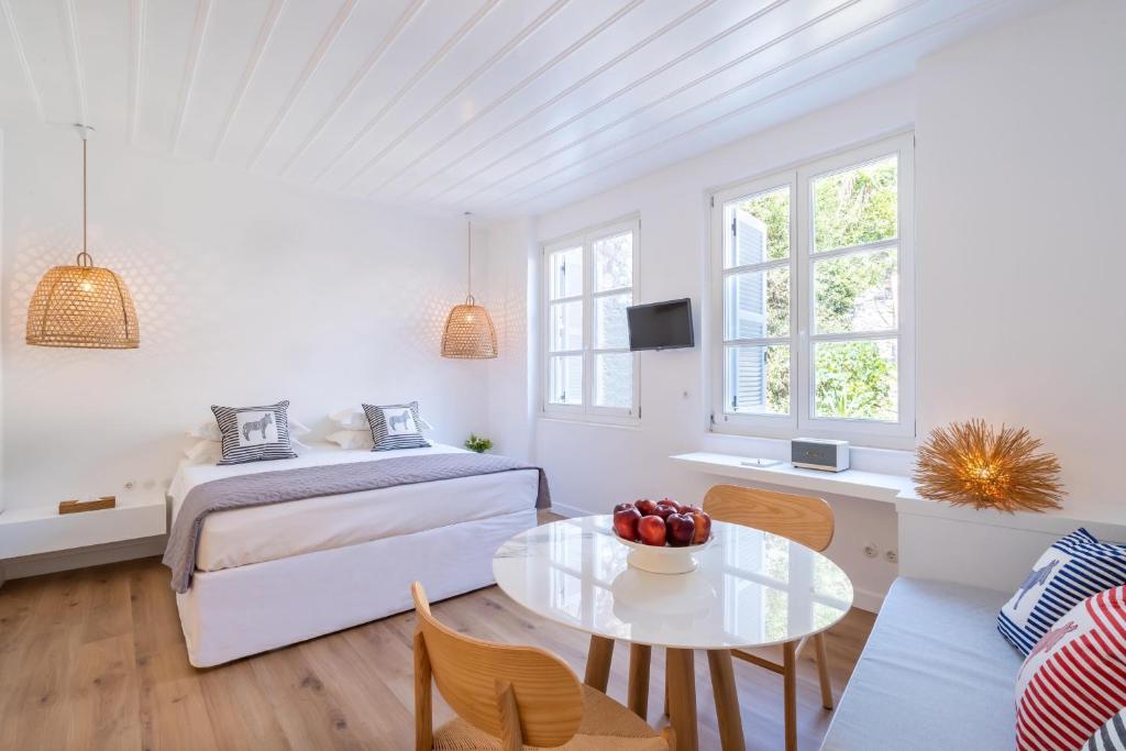 a white bedroom with a bed and a table at Upper Hydra in Hydra