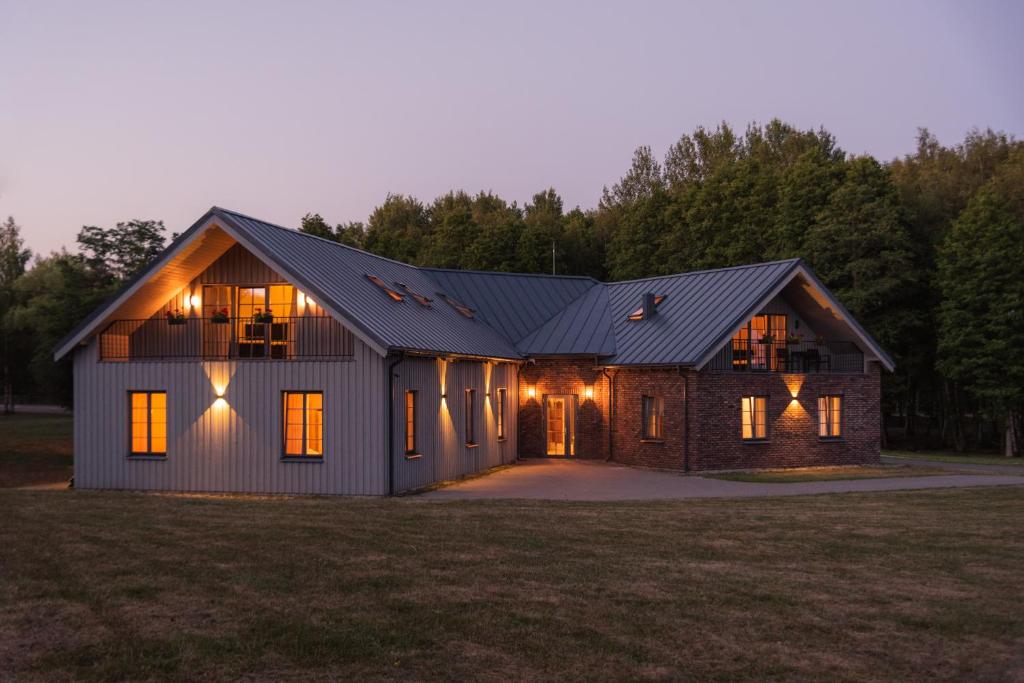 a house with a gambrel roof with a garage at Lake & Library Hotel in Ignalina