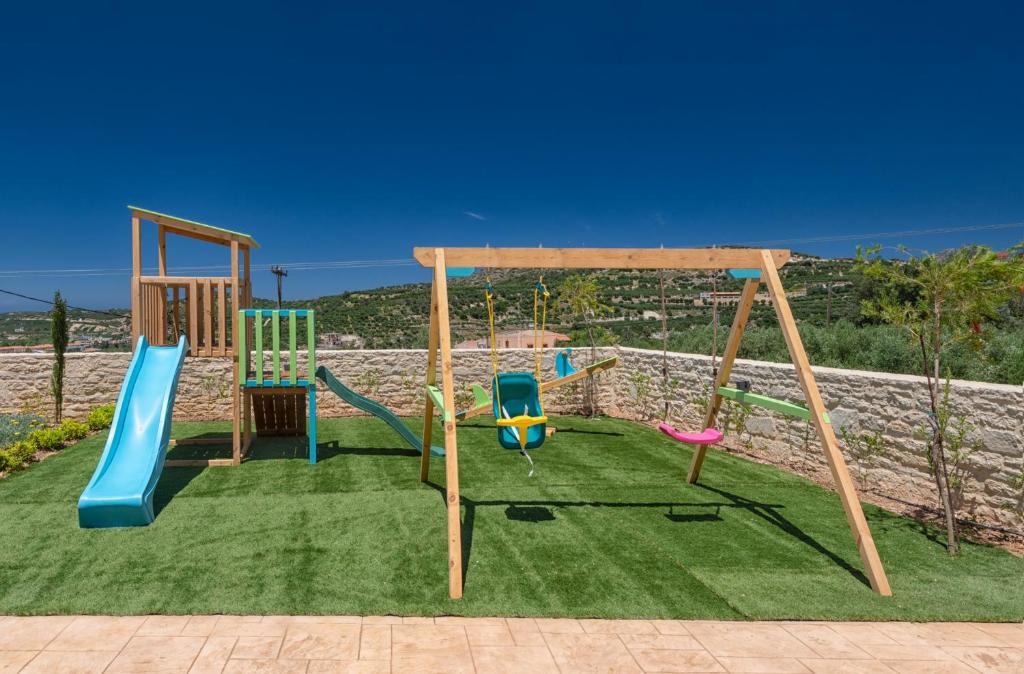 plac zabaw ze zjeżdżalniami i huśtawkami na trawniku w obiekcie Ivoni Villa, an Iconic Summer Retreat, By ThinkVilla w mieście Perama