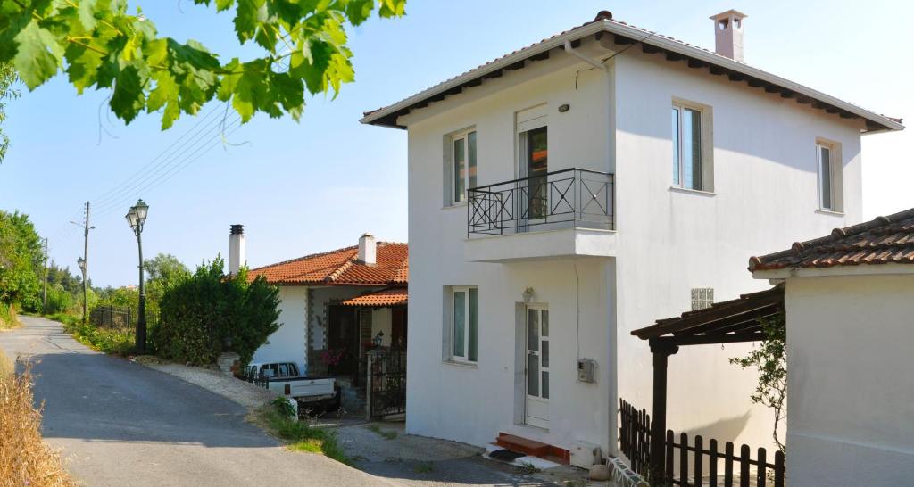 Casa blanca con balcón en una calle en Village Holiday House Nick, en Agia Paraskevi