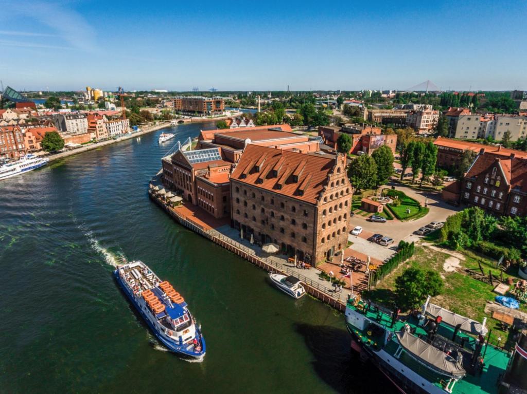 een boot is aangemeerd op een rivier in een stad bij Jess Hotel Krolewski Gdansk Old Town in Gdańsk