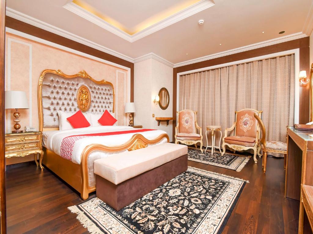 a bedroom with a king sized bed and two chairs at Ras Al Khaimah Hotel in Ras al Khaimah