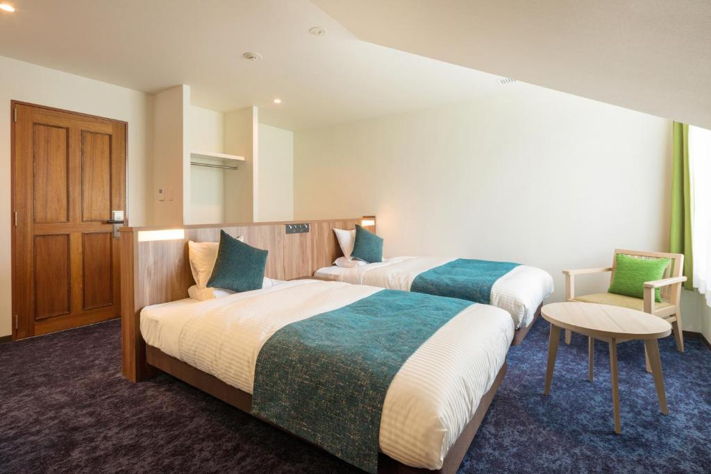 um quarto de hotel com duas camas e uma cadeira em Tazawako Lake Resort & Onsen em Senboku