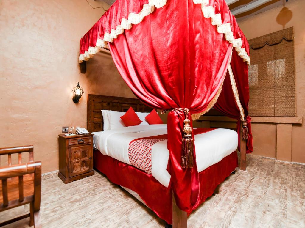 a bedroom with a canopy bed with red curtains at Ras Al Khaimah Hotel in Ras al Khaimah