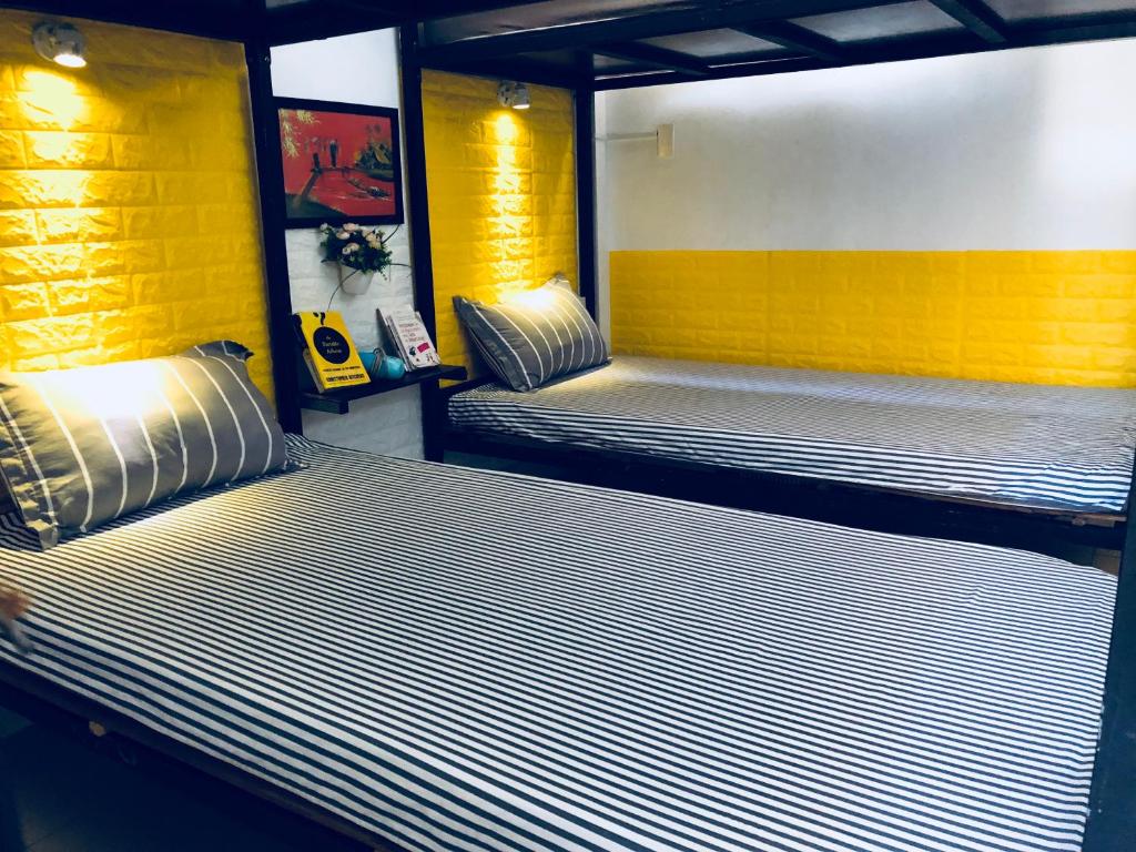 two beds in a room with yellow and white stripes at Friendly House Hostel in Hue