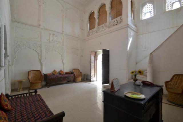 Cette grande chambre blanche dispose d'une table et de chaises. dans l'établissement Rawla Mrignayani Palace, à Jaipur