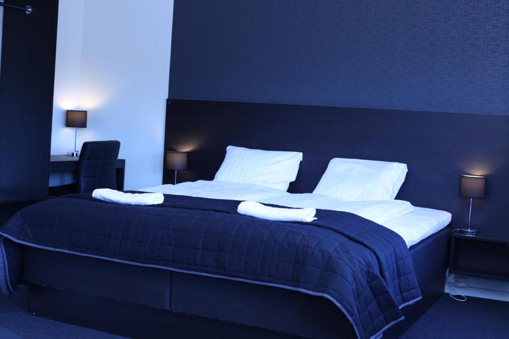 a bedroom with a large bed with white sheets and pillows at Nacka Stadshotell in Nacka