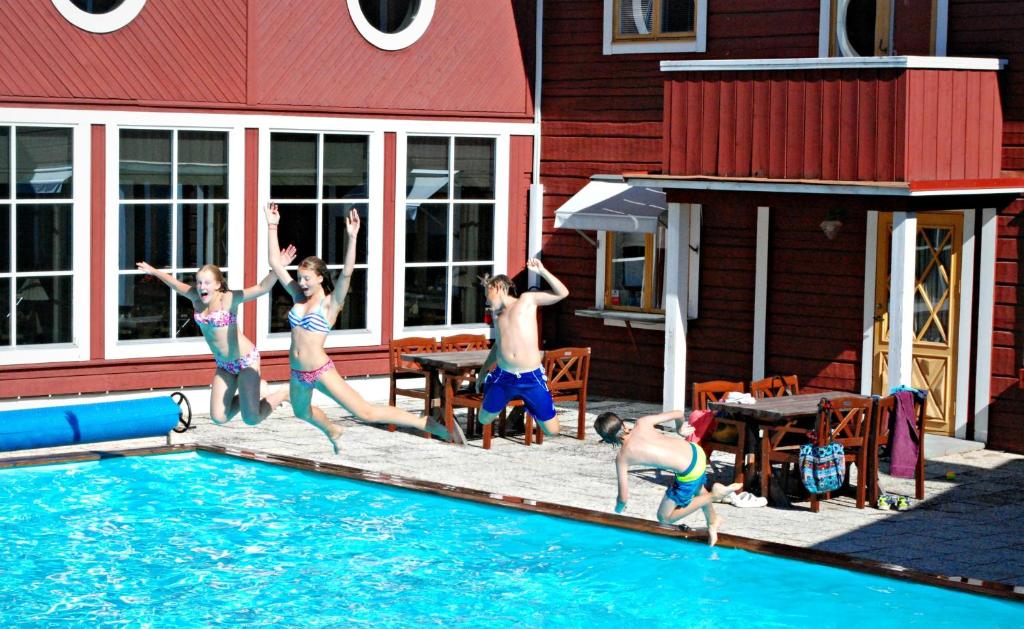 a group of people jumping into a swimming pool at Hotell Moskogen in Leksand