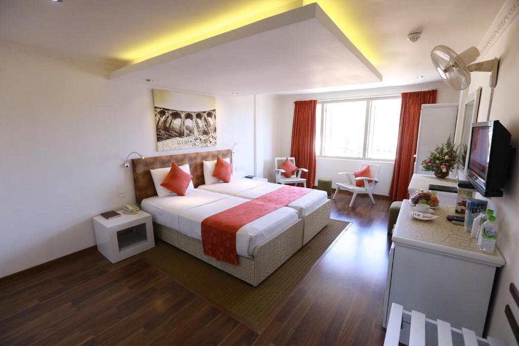 Habitación de hotel con cama y TV en Orient Hotel, en Bandarawela