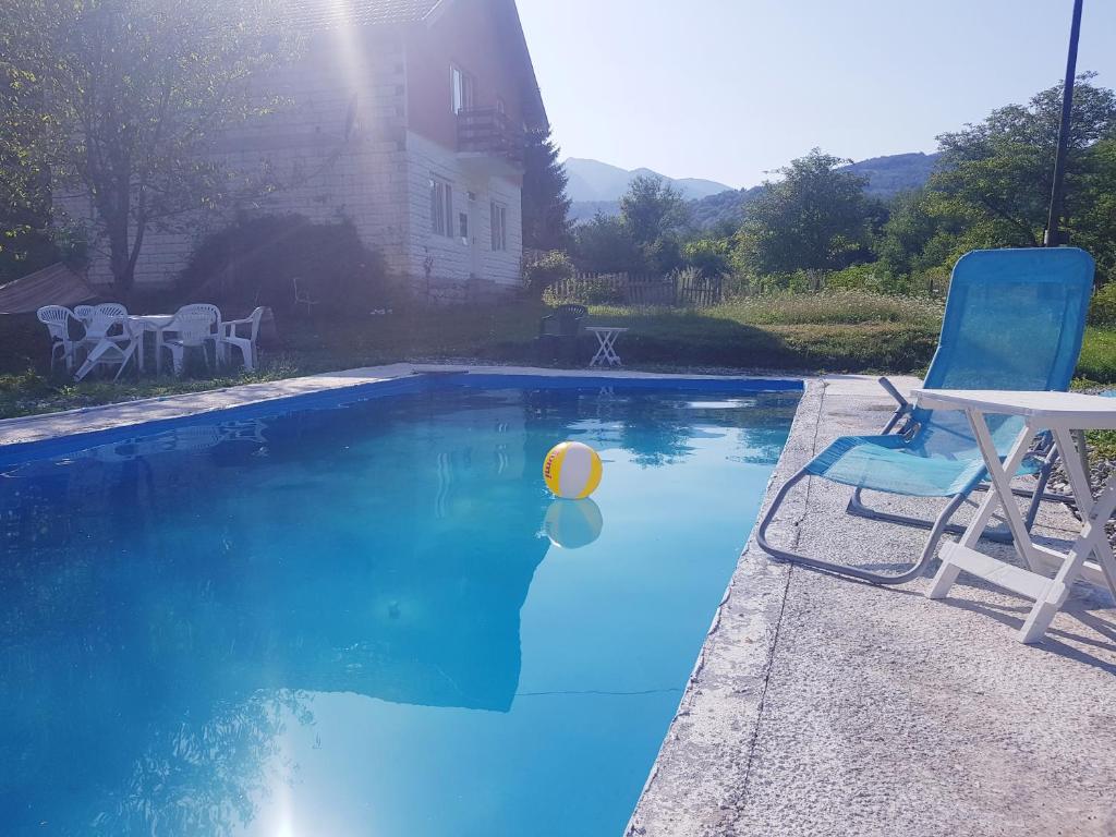 a blue swimming pool with a chair and a ball in it at Turistički kompleks Radovic- Vila Lara in Tjentište