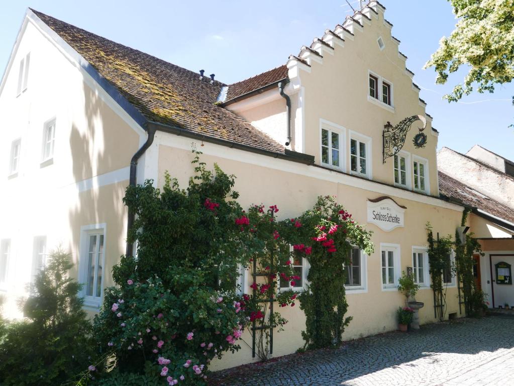 un bâtiment avec des fleurs devant lui dans l'établissement Schloss - Schenke Tunzenberg, à Mengkofen