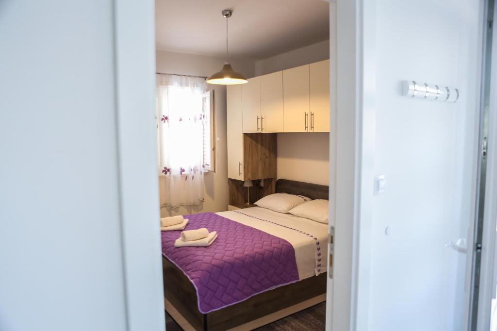 Un dormitorio con una cama con sábanas moradas y una ventana. en Apartman Diva, en Orebić
