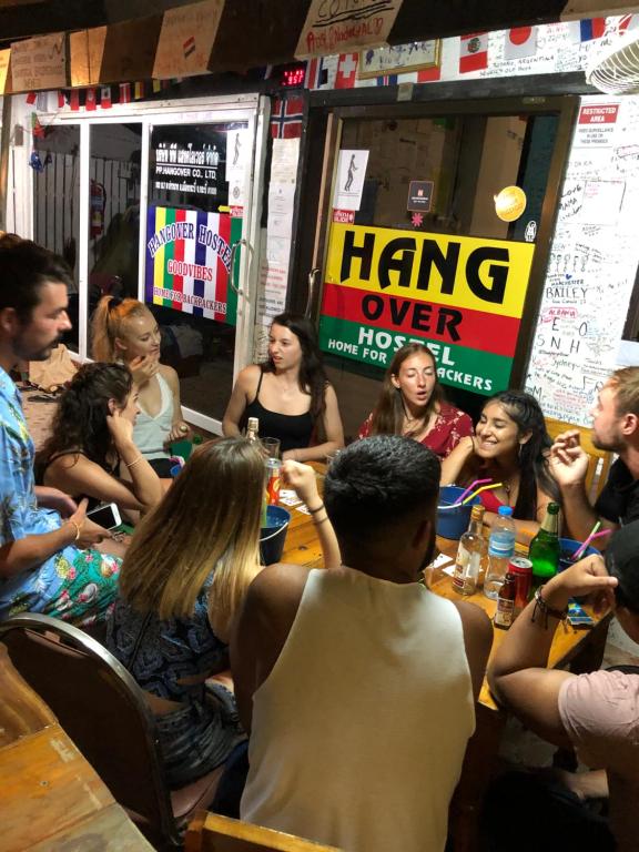 eine Gruppe von Menschen, die in einem Restaurant an einem Tisch sitzen in der Unterkunft Hangover Hostel in Ko Phi Phi