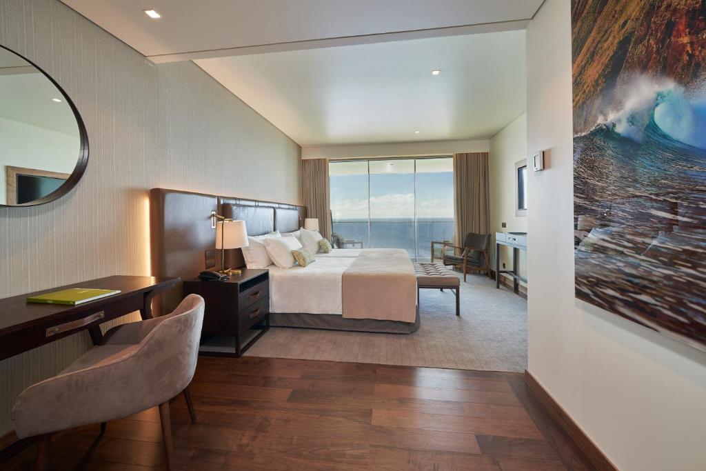 a hotel room with a bed and a large window at Les Suites at The Cliff Bay - PortoBay in Funchal