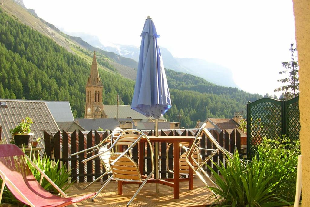 a table and chairs on a deck with a umbrella at Le Serre Grou studioLarge studio at the gateway to the Ecrins National Park in Villar-dʼArène