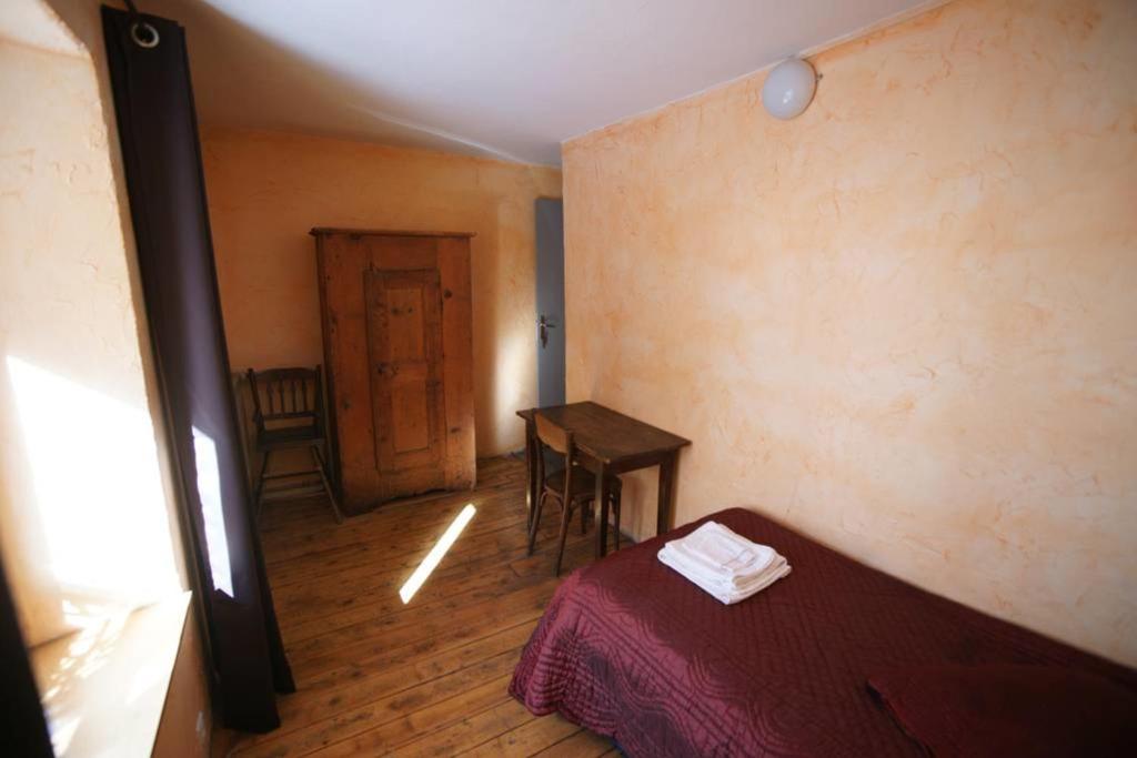 a room with a bed and a table and a door at Chez Jean Pierre - Room 1pers in a 17th century house - n 6 in Villar-dʼArène