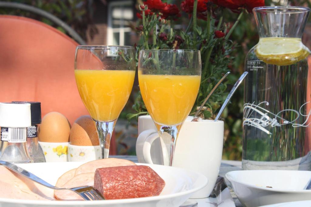 twee glazen sinaasappelsap en brood op een tafel bij Bed & Breakfast Op 't Leven in Ermelo