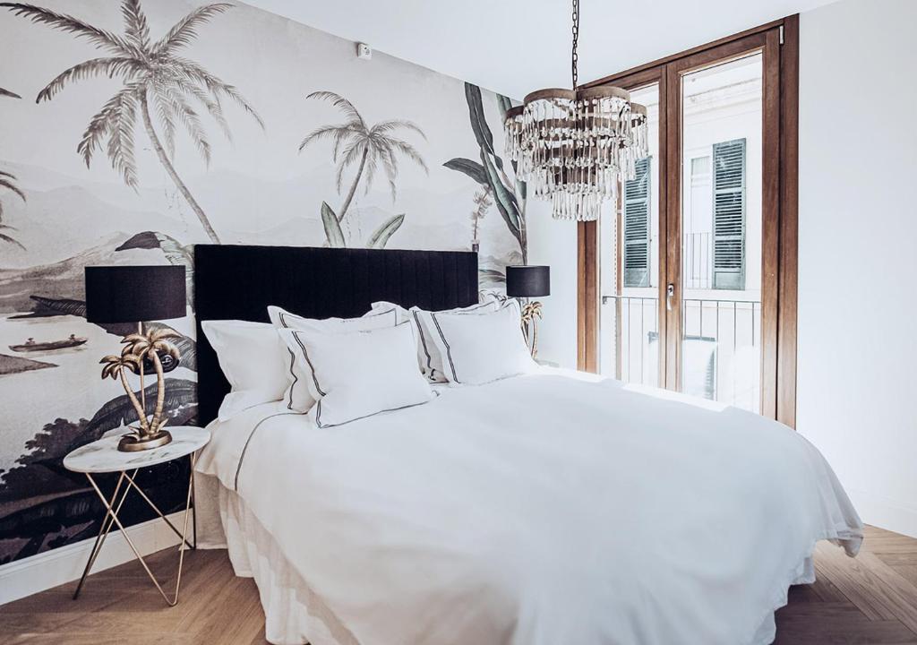una camera da letto con un grande letto bianco e un lampadario a braccio di Ocho Suites & Kitchen a Palma de Mallorca