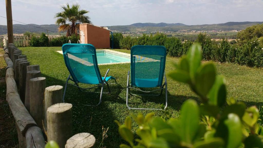 duas cadeiras azuis sentadas ao lado de uma piscina em Can Cruset agroturisme em Torrellas de Foix