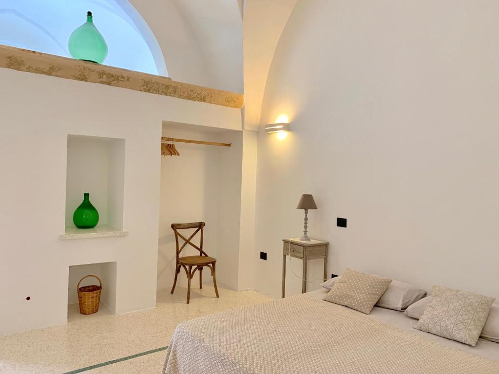 a white bedroom with a bed and a chair at Casa Vacanze Il Pumo in Corsano